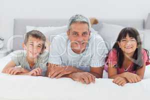 Father with his children lying on bed