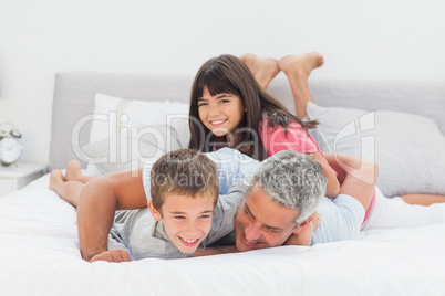 Father having fun with his children on bed