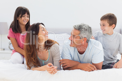 Smiling family talking together on bed