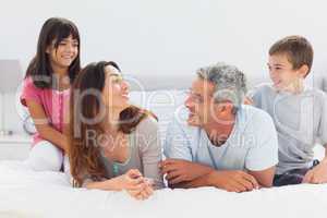 Smiling family talking together on bed