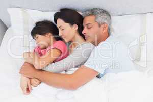 Parents sleeping with their daughter in bed
