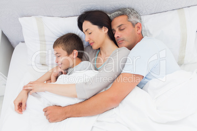 Parents sleeping with their son in bed