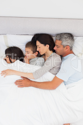 Parent sleeping with their children in bed