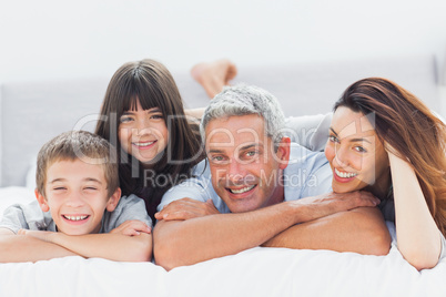 Cute family lying on bed and smiling at camera