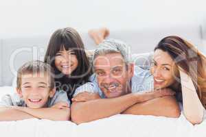 Cute family lying on bed and smiling at camera
