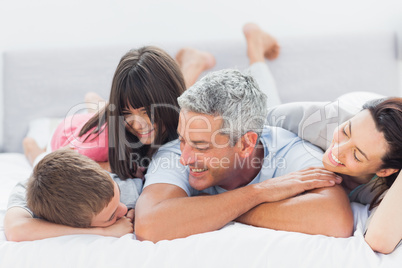 Cute family lying on bed and talking together