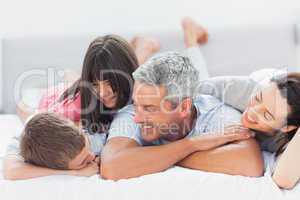 Cute family lying on bed and talking together