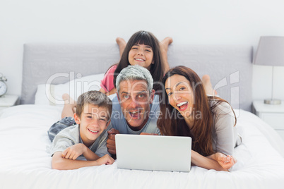 Funny family lying on bed using their laptop