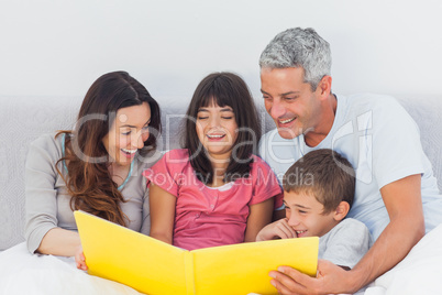 Family looking together at their photograph album in bed