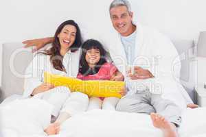 Parents with their daughter on bed looking together at photograp