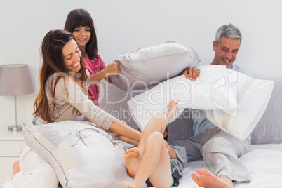 Family fighting together with pillows on bed