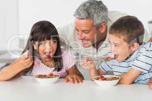 Smiling father talking with his children during their breakfast