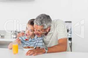 Father and son eating cereal together during breakfast
