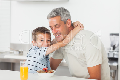 Little boy giving hug to his father during breakfast