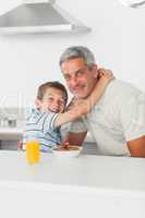 Smiling little boy giving hug to his father during breakfast