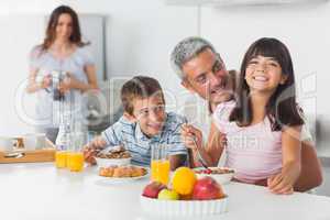 Smiling family eating breakfast in kitchen together