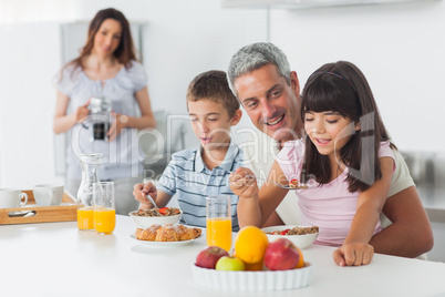 Happy family eating breakfast in kitchen together