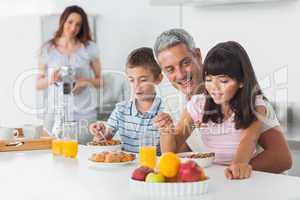 Happy family eating breakfast in kitchen together