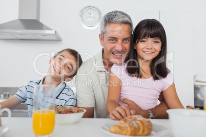 Siblings eating breakfast in kitchen together with dad