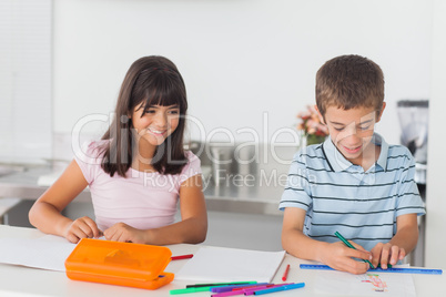 Smiling siblings drawing in kitchen