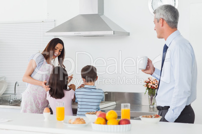 Father looking at his family cooking in the kitchen