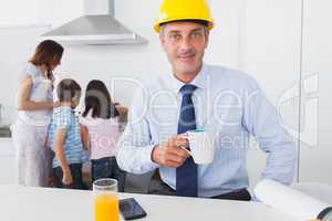 Father wearing hardhat and drinking coffee at home with his fami