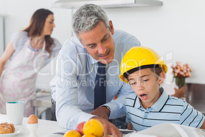 Father showing son his blueprints as he is wearing hardhat