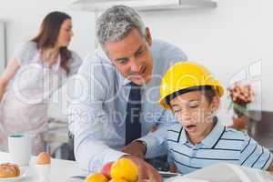 Father showing son his blueprints as he is wearing hardhat