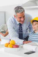 Father showing son his blueprints as he is wearing yellow helmet