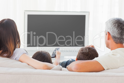 Family sitting on sofa watching television together