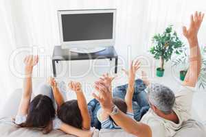 Family raising their arms in front of television