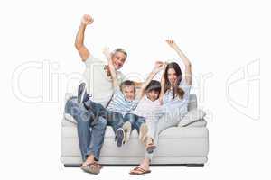 Family sitting on sofa raising their arms