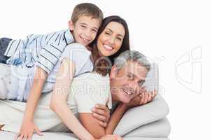 Smiling little boy lying on his parents on sofa