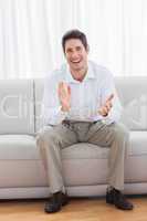 Young man sitting on sofa applauding