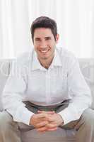 Cheerful young man sitting on sofa