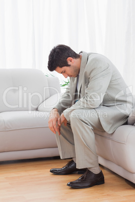 Troubled buinessman sitting on sofa lowering his head