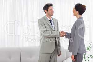 Smiling colleagues shaking hands during meeting