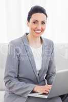 Smiling busineswoman using laptop sitting on sofa