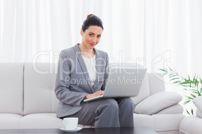 Smiling busineswoman sitting on sofa using laptop
