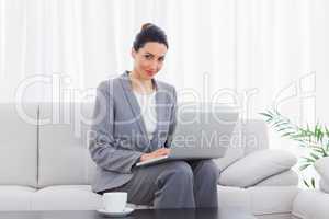 Smiling busineswoman sitting on sofa using laptop