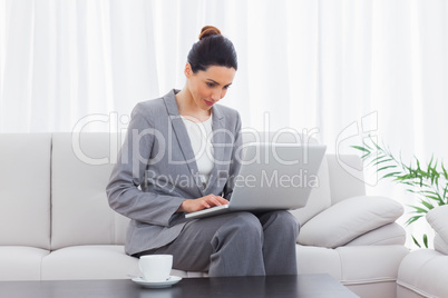 Busineswoman sitting on sofa using laptop