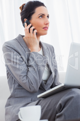 Businesswoman calling with her mobile phone and using laptop sit