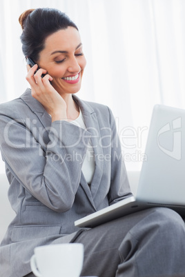 Smiling businesswoman calling with her mobile phone and using la