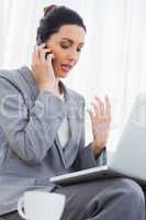 Concentrated businesswoman calling with her mobile phone and usi