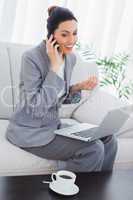 Happy businesswoman calling with her mobile phone and using lapt