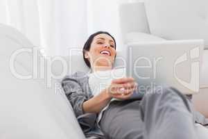 Relaxing businesswoman lying on sofa using laptop