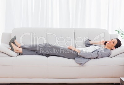 Businesswoman lying on sofa calling with her mobile phone