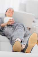 Businesswoman lying on sofa with her laptop