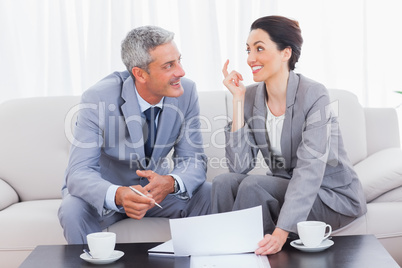 Happy business people working and talking together on sofa