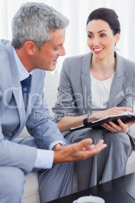 Smiling business people working and talking together on sofa